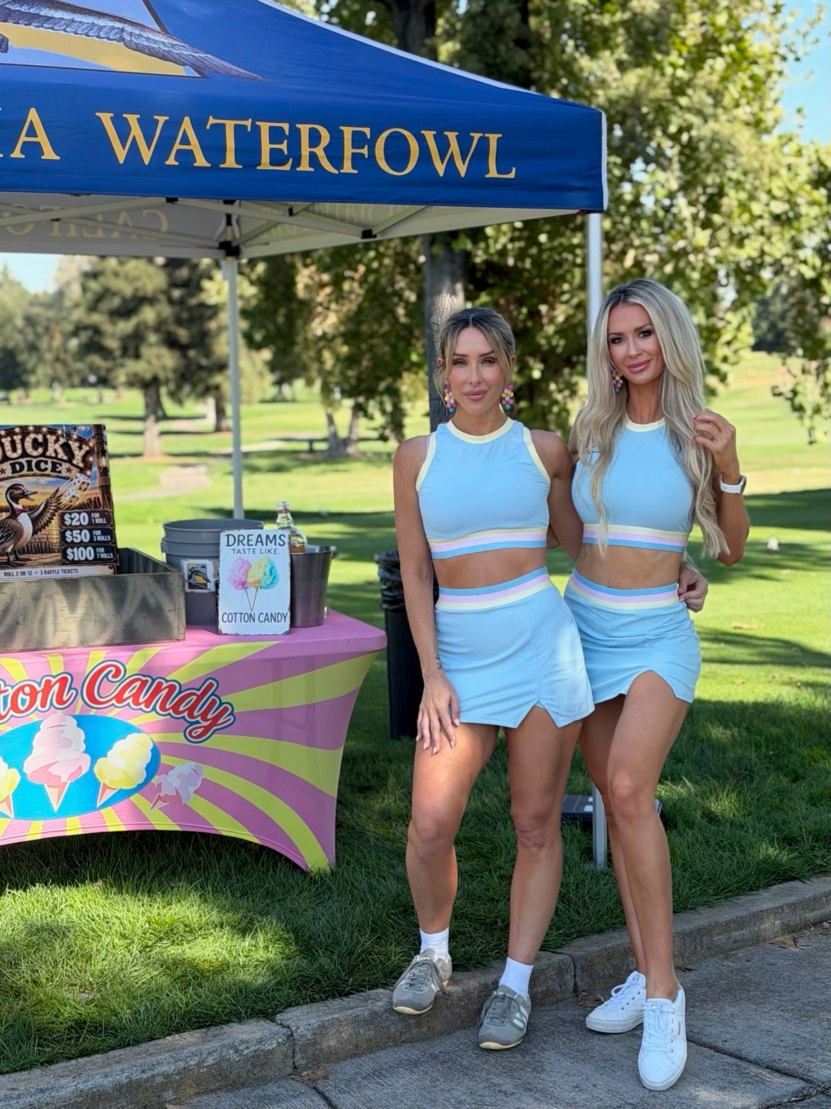 Two Mandi's Models in matching pastel outfits beside a cotton candy table on a golf course